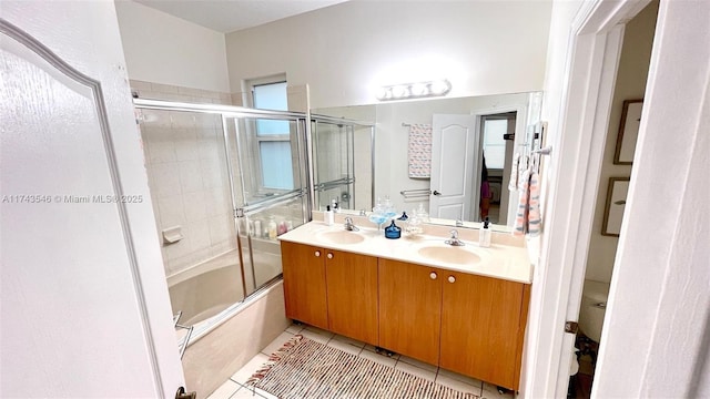 bathroom with tile patterned floors, enclosed tub / shower combo, double vanity, and a sink