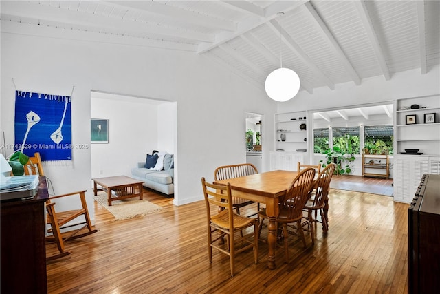 dining space with lofted ceiling with beams, hardwood / wood-style floors, and built in features