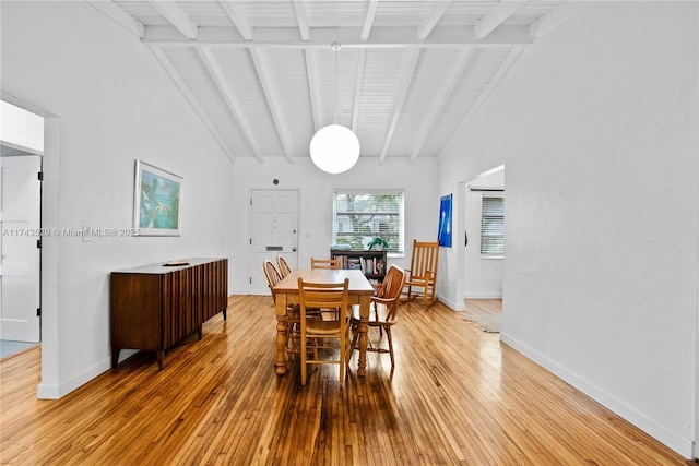 dining space with high vaulted ceiling, hardwood / wood-style floors, and beam ceiling