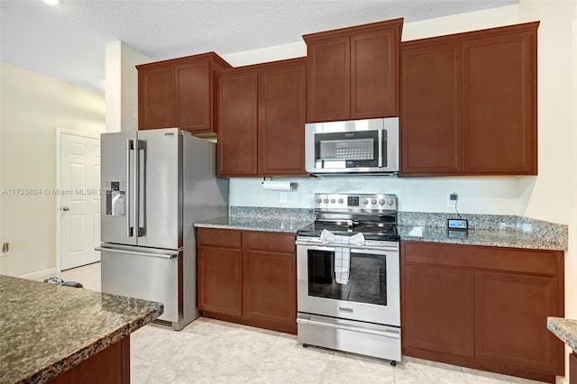 kitchen featuring dark stone counters, a textured ceiling, and appliances with stainless steel finishes