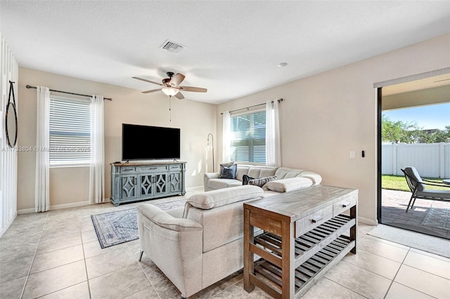 living room with light tile patterned floors, a textured ceiling, and ceiling fan