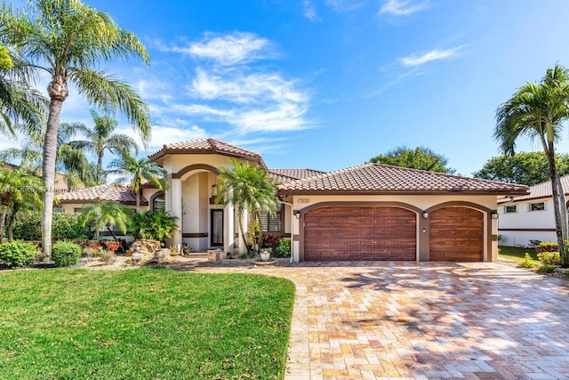 mediterranean / spanish house with a garage and a front lawn