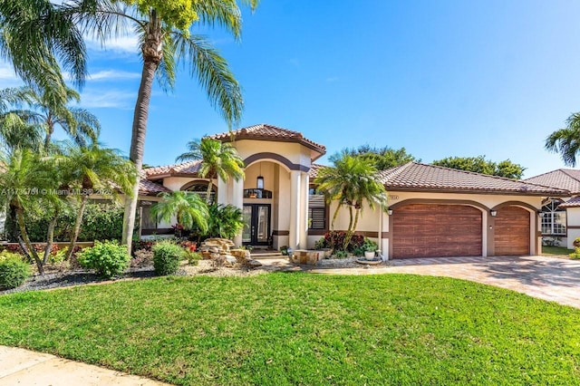 mediterranean / spanish-style home with a garage, a front yard, and french doors