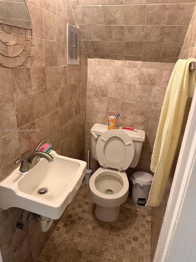 bathroom featuring sink, tile walls, and toilet