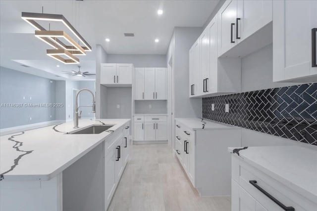 kitchen with white cabinetry, sink, backsplash, and ceiling fan