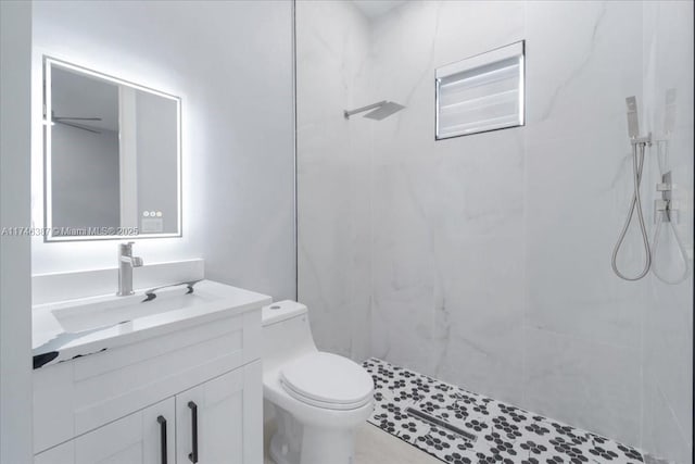 bathroom with tiled shower, vanity, and toilet