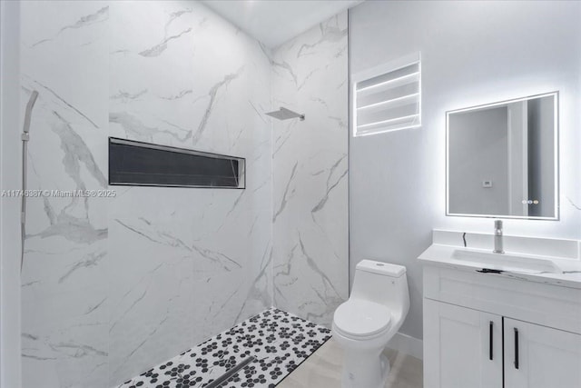 bathroom featuring vanity, toilet, and a tile shower