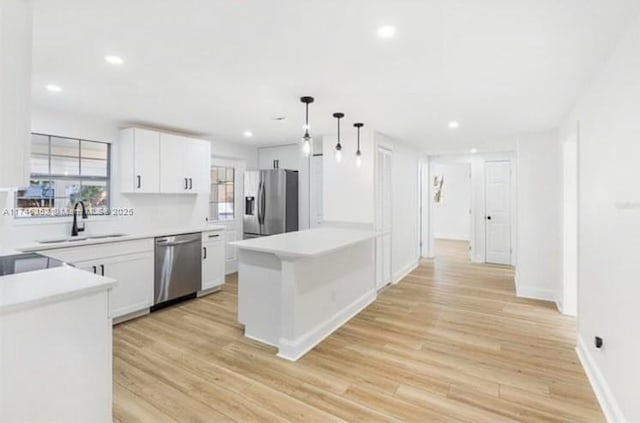 kitchen featuring stainless steel appliances, white cabinetry, hanging light fixtures, and sink