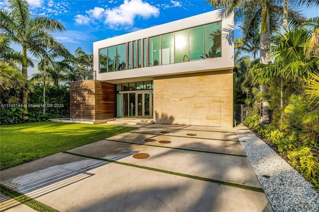 rear view of property featuring french doors, a lawn, and a balcony