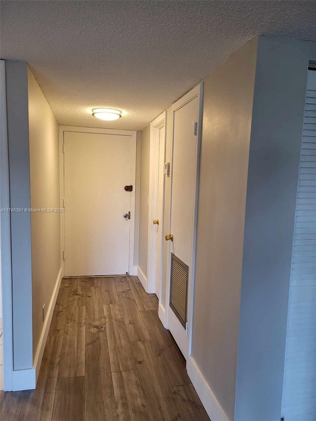 hall with hardwood / wood-style flooring and a textured ceiling