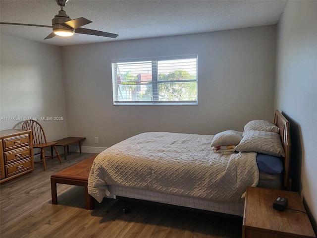 bedroom featuring ceiling fan, hardwood / wood-style floors, and a textured ceiling