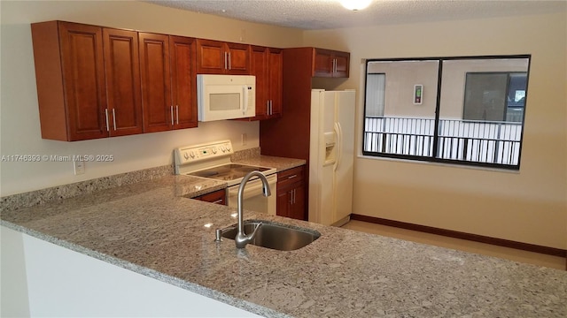 kitchen featuring sink, light stone counters, a textured ceiling, kitchen peninsula, and white appliances