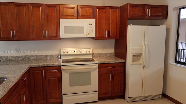 kitchen featuring light stone counters and white appliances