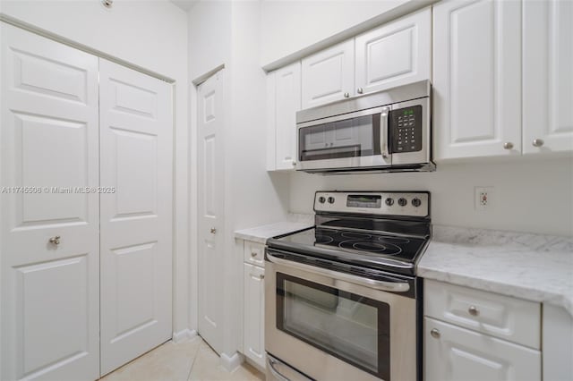 17100 N Bay Rd Unit 1303, Sunny Isles Beach, FL 33160 - kitchen with appliances with stainless steel finishes, white cabinetry, light tile patterned floors, and light stone counters