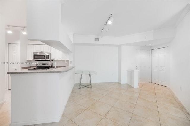 kitchen with light tile patterned floors, crown molding, appliances with stainless steel finishes, white cabinets, and kitchen peninsula