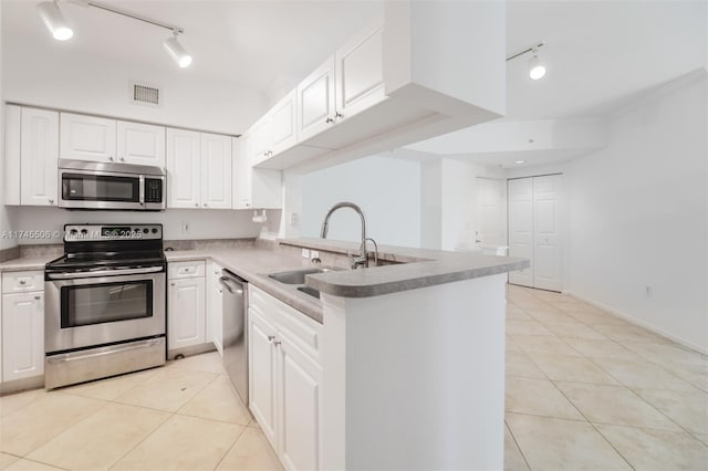 kitchen featuring sink, light tile patterned floors, kitchen peninsula, stainless steel appliances, and white cabinets