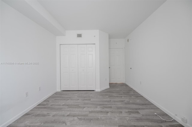 unfurnished bedroom featuring light hardwood / wood-style floors and a closet