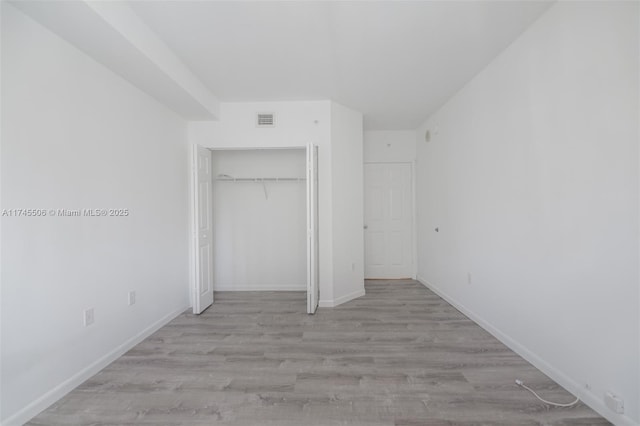 unfurnished bedroom featuring light wood-type flooring and a closet