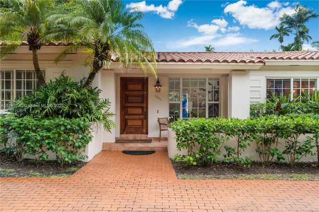 property entrance with a tile roof and stucco siding