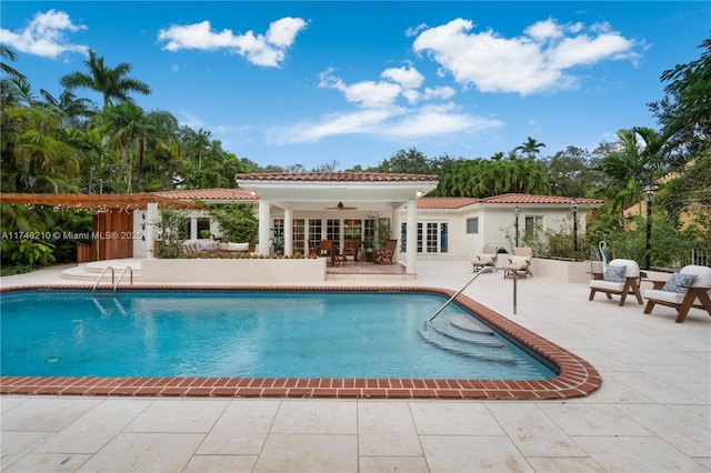 outdoor pool with french doors, a patio area, and ceiling fan