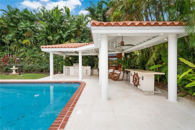 outdoor pool with an outdoor kitchen, area for grilling, a ceiling fan, a gazebo, and a patio area