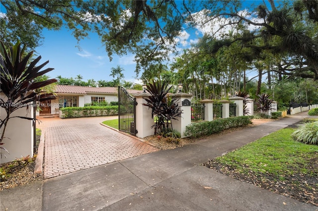 mediterranean / spanish home featuring a fenced front yard, a gate, and stucco siding