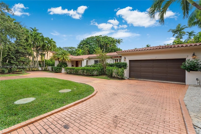 view of front of home with stucco siding, a tiled roof, an attached garage, decorative driveway, and a front yard