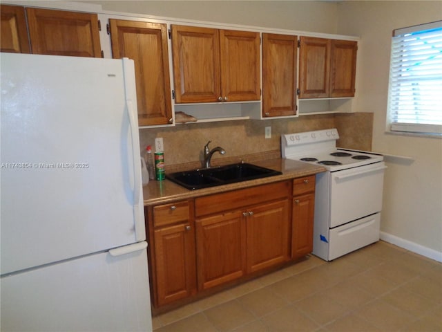 kitchen with white appliances, brown cabinets, and a sink