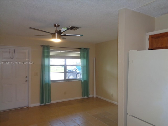 unfurnished room featuring baseboards, ceiling fan, visible vents, and a textured ceiling