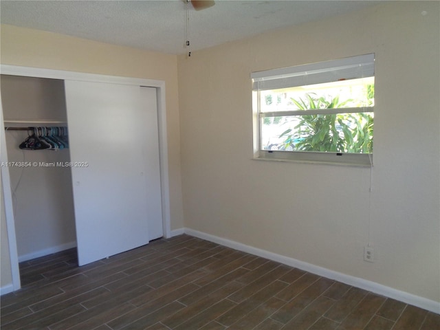 unfurnished bedroom with wood tiled floor, baseboards, and a closet