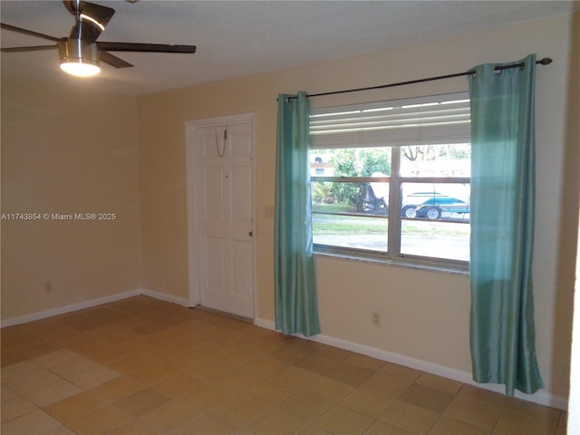 unfurnished room with a ceiling fan and baseboards