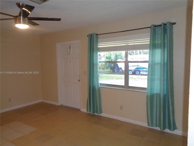 unfurnished room with a ceiling fan and baseboards