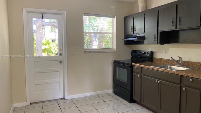 kitchen featuring light tile patterned floors, under cabinet range hood, black range with electric stovetop, a sink, and dark countertops