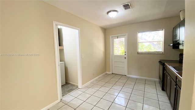 kitchen featuring black / electric stove, light tile patterned floors, dark countertops, visible vents, and baseboards