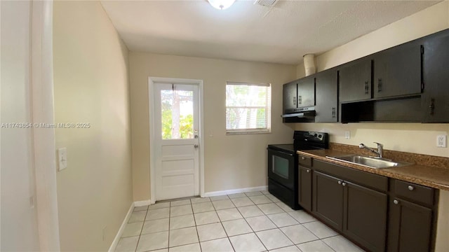 kitchen featuring dark countertops, electric range, a sink, under cabinet range hood, and baseboards