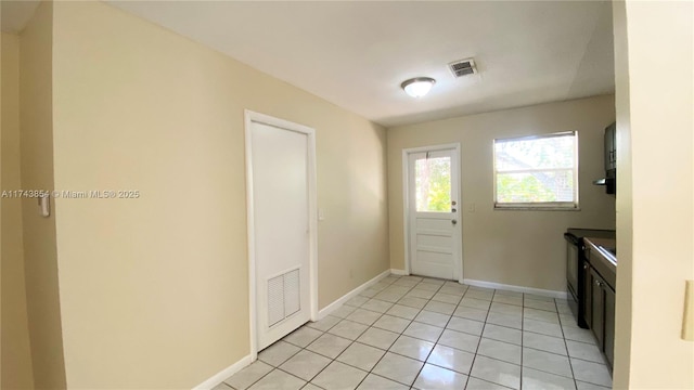 doorway to outside featuring visible vents, baseboards, and light tile patterned floors