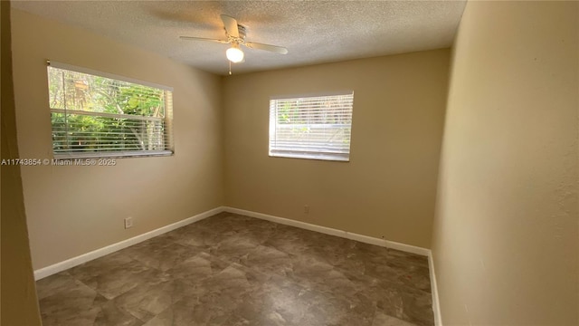 spare room featuring baseboards, a textured ceiling, and a healthy amount of sunlight