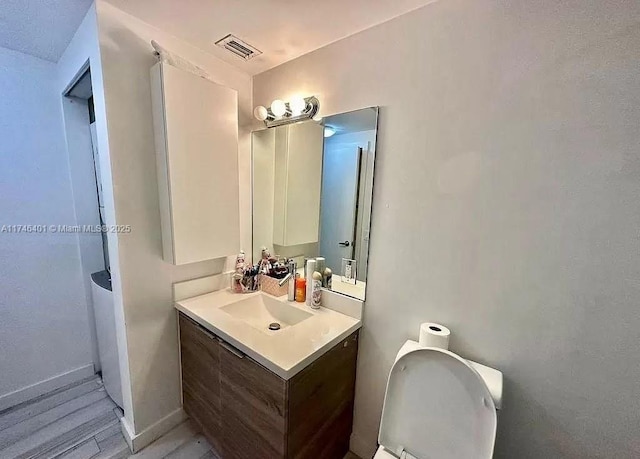 bathroom with vanity, toilet, and hardwood / wood-style floors