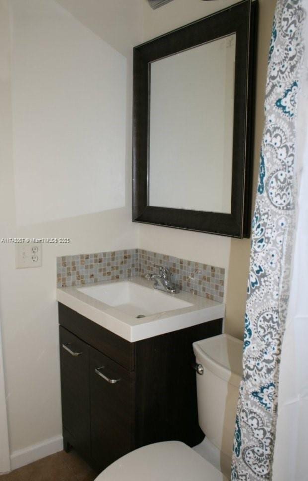 bathroom with vanity, backsplash, and toilet