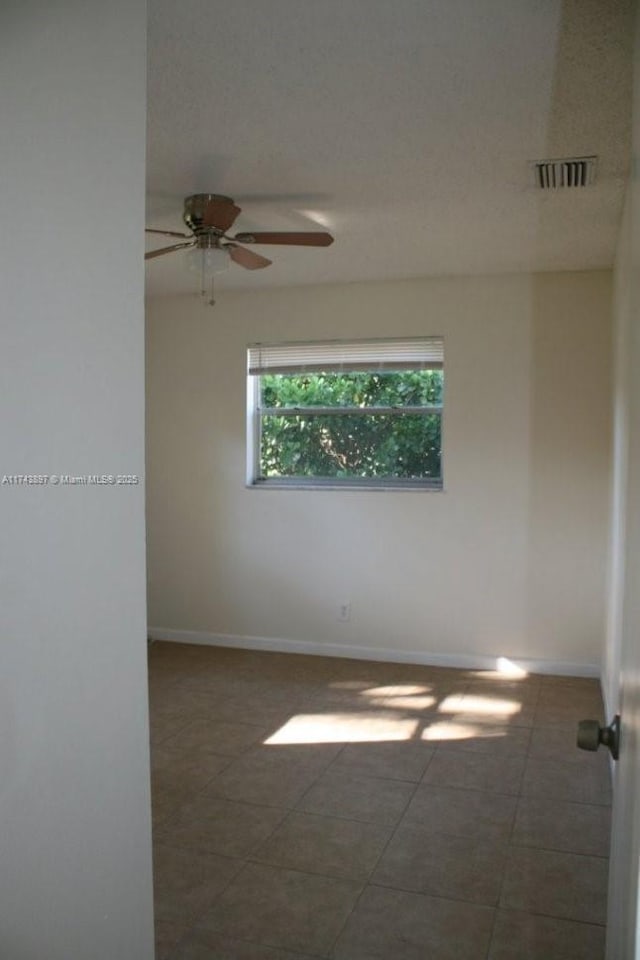 unfurnished room with dark tile patterned floors and ceiling fan