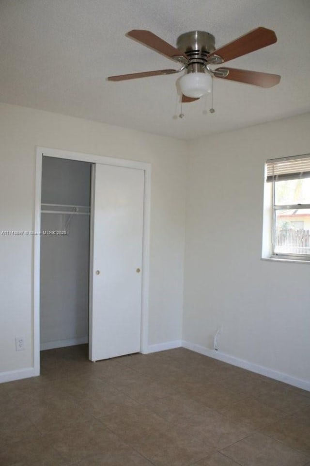 unfurnished bedroom with ceiling fan and a closet