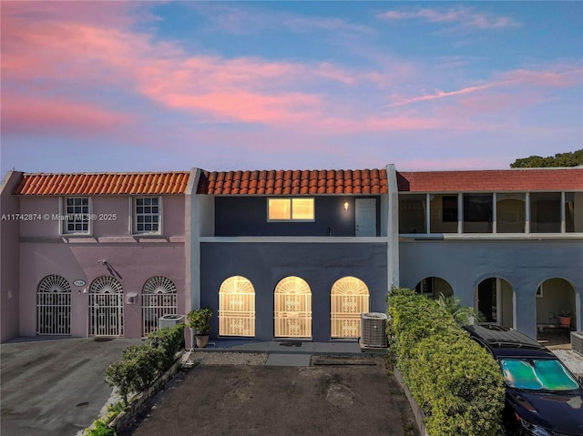 view of front of home with stucco siding, fence, a gate, and central air condition unit