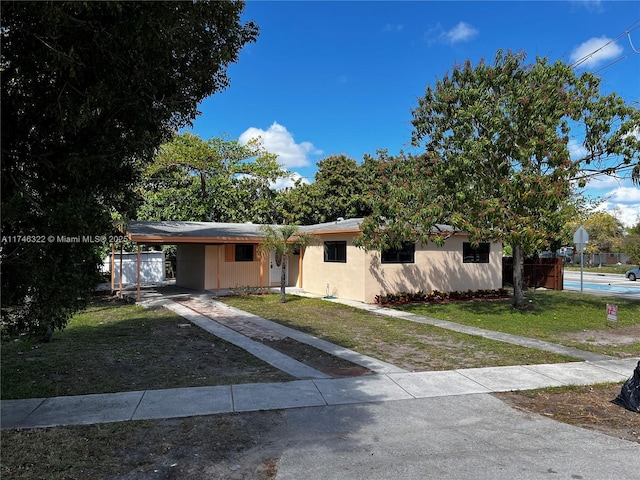 ranch-style house with a carport, a front lawn, and fence