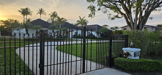 gate at dusk featuring a lawn