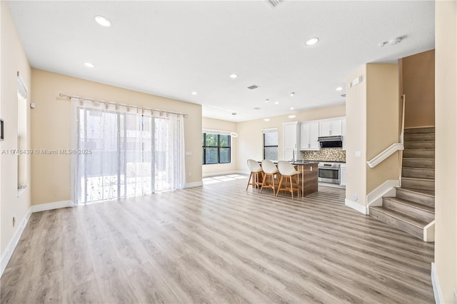 unfurnished living room featuring light wood-type flooring and sink