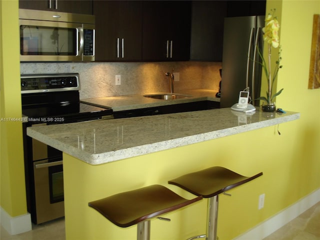 770 Claughton Island Dr Unit 1708, Miami, FL 33131 - kitchen with stainless steel appliances, a sink, baseboards, decorative backsplash, and a breakfast bar