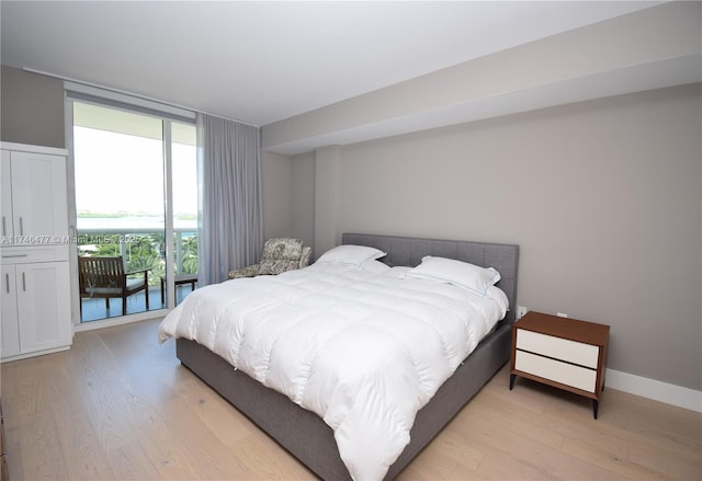 bedroom with floor to ceiling windows, access to exterior, and light hardwood / wood-style floors