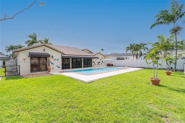 rear view of house with a fenced in pool and a yard