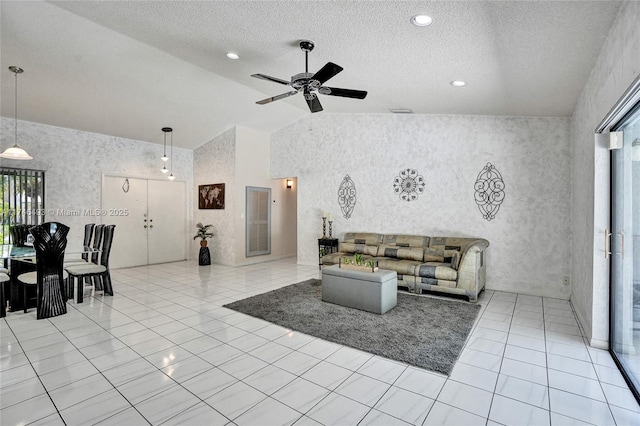 living room with light tile patterned flooring, lofted ceiling, ceiling fan, and a textured ceiling