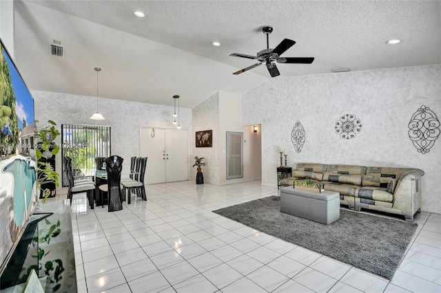 tiled living room with ceiling fan, high vaulted ceiling, and a textured ceiling